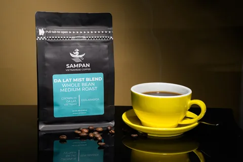 Sampan Da Lat Mist Blend coffee bag standing beside a yellow cup of brewed Vietnamese coffee